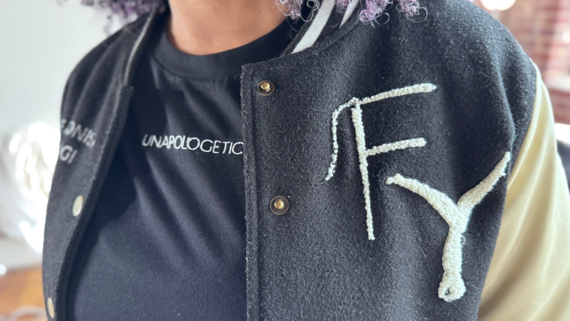 Suleah wearing an embroidered varsity jacket over an unapologetic tee