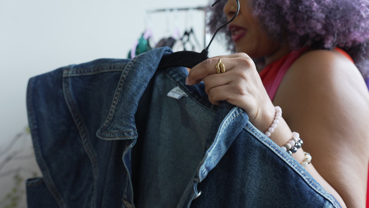 Suleah holding a denim jacket in her Life + Style Studio